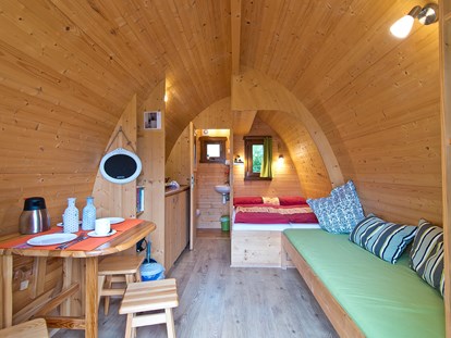 Luxury camping - Kochutensilien - Niederrhein - Sitzecke, Doppelbett und Couch im Pod © Campingpark Kerstgenshof - Campingpark Kerstgenshof Pods auf dem Campingpark Kerstgenshof