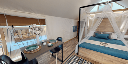 Luxuscamping - Terrasse - Kärnten - Lakeside romantic Tent Schlafzimmer mit Doppelbett und der Sitz- bzw. Essbereich - Lakeside Petzen Glamping Resort Lakeside romantic Tent im Lakeside Petzen Glamping Resort