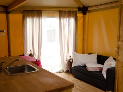 Luxury camping - barrierefreier Zugang - Italy - Glamping-Zelte: Wohnzimmer mit Tisch, Stühlen, Spülbecken, Kühlschrank (ohne Küche) und Schlafsofa - Camping Rialto Glampingzelte auf Camping Rialto