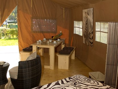 Luxuscamping - Umgebungsschwerpunkt: See - Deutschland - Blick vom Safarizelt auf die Terrasse. Dort gibt es ebenfalls einen langen Tisch und Bänke - für ein Abendessen bei Sonnenuntergang. - Camping Park Gohren
