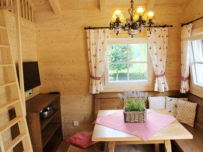 Luxury camping - Kiosk - Ferienhütte "Drachenwand": gemütliche Sitzecke mit Fernseher (SAT-Anlage) und Aufgang zur Galerie mit Schlafmöglichkeit - CAMP MondSeeLand