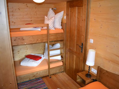 Luxury camping - barrierefreier Zugang ins Wasser - Ferienhütte "Schober": Schlafzimmer mit Doppelbett und einem Stockbett - CAMP MondSeeLand