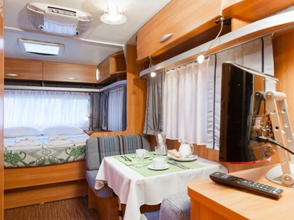Luxuscamping - Venetien - Wohnzimmer und Doppelbett - Camping Ca' Pasquali Village Caravan Pinienwald auf Camping Ca' Pasquali Village