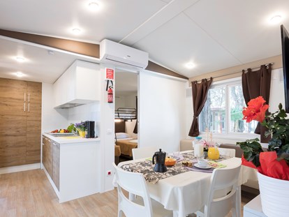 Luxuscamping - Terrasse - Cavallino - Wohnzimmer mit Küche und im unteren Schlafzimmer der Kinder - Camping Vela Blu Mobilheim Top Residence Platinum auf Camping Vela Blu