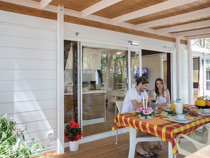 Luxuscamping - Sonnenliegen - Italien - Außenansicht des Mobilheims mit Terrasse - Camping Vela Blu Mobilheim Top Residence Platinum auf Camping Vela Blu