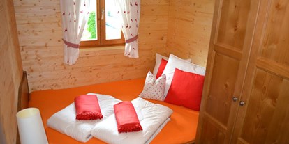 Luxuscamping - Art der Unterkunft: Bungalow - Ferienhütte "Schober": Schlafzimmer mit Doppelbett und einem Stockbett - CAMP MondSeeLand Ferienhütten am CAMP MondSeeLand