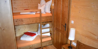 Luxuscamping - Salzburg - Seenland - Ferienhütte "Schober": Schlafzimmer mit Doppelbett und einem Stockbett - CAMP MondSeeLand Ferienhütten am CAMP MondSeeLand