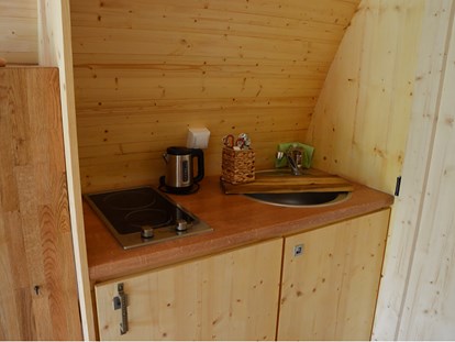 Luxury camping - Küche mit Kochplatten, Spüle und Kühlschrank mit Eisfach - Naturcampingpark Rehberge Glamping-Pod Waldemar am Wurlsee - Naturcampingpark Rehberge