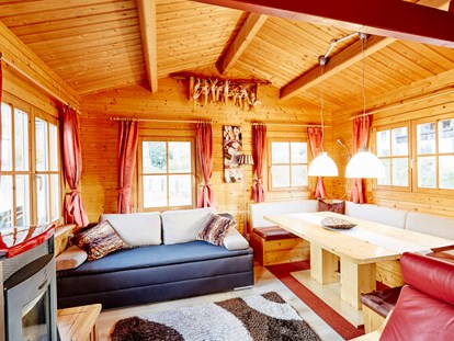 Luxury camping - Art der Unterkunft: Bungalow - Oberinntal - Wohnbereich mit gemütlicher Sitzecke Pelletsofen, ausziehbarer Couch - Camping Dreiländereck in Tirol Blockhütte Tirol Camping Dreiländereck Tirol