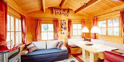 Luxuscamping - Art der Unterkunft: Bungalow - Wohnbereich mit gemütlicher Sitzecke Pelletsofen, ausziehbarer Couch - Camping Dreiländereck in Tirol Blockhütte Tirol Camping Dreiländereck Tirol