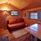 Glampingunterkunft: ausziehbare Couch, gemütlicher Ess- Sitzbereich - Camping Dreiländereck in Tirol: Kleine Blockhütte Camping Dreiländereck Tirol