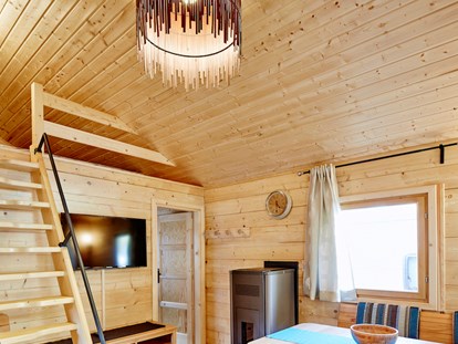 Luxuscamping - Wohnbereich mit Aufgang zum Schlafboden bzw. Relaxlounge, gemütliche Sitzecke mit Blick zum Flat-TV, Pelletsofen - Blockhütte Bergzauber Camping Dreiländereck Tirol