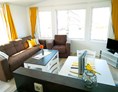 Glampingunterkunft: Wohnzimmer mit Sat-TV und gemütlicher Couch - Bungalow Möwe am Ostseecamp Seeblick