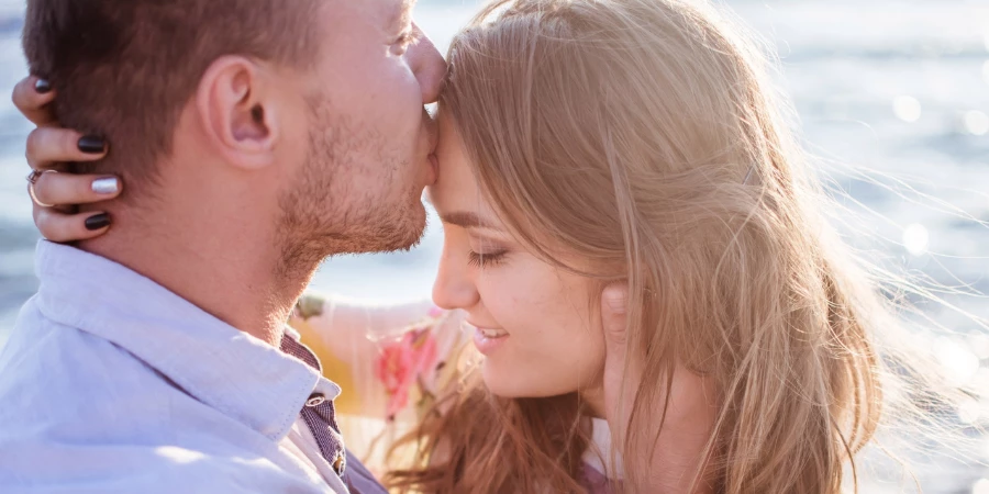 Mann küsst Frau verliebt auf die Stirn