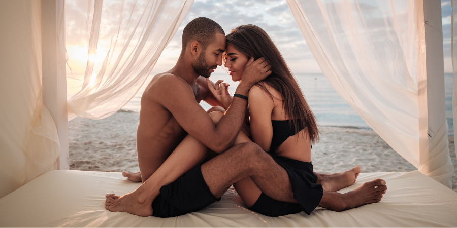 Paar sitzt auf einem Bett am Strand