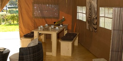 Luxuscamping - Art der Unterkunft: Safari-Zelt - PLZ 88079 (Deutschland) - Blick vom Safarizelt auf die Terrasse. Dort gibt es ebenfalls einen langen Tisch und Bänke - für ein Abendessen bei Sonnenuntergang. - Camping Park Gohren Safarizelte Camping Park Gohren