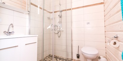 Luxuscamping - WLAN - Badezimmer im Ferienhäuschen mit bodentiefer Regendusche, WC und Spiegelschrank.  - Ostseecamping Ferienpark Zierow