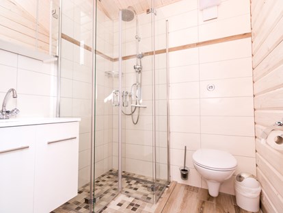 Luxuscamping - Badezimmer im Ferienhäuschen mit bodentiefer Regendusche, WC und Spiegelschrank.  - Ostseecamping Ferienpark Zierow