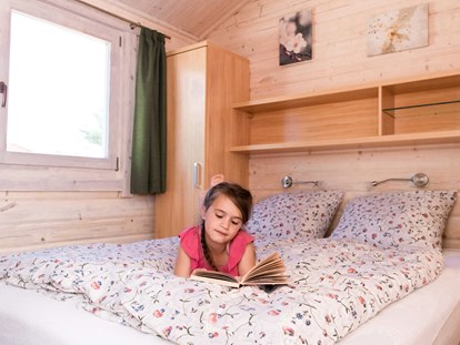 Luxuscamping - Umgebungsschwerpunkt: Meer - Schlafzimmer mit Doppel-Boxspringbett im Ferienhäuschen - Ostseecamping Ferienpark Zierow