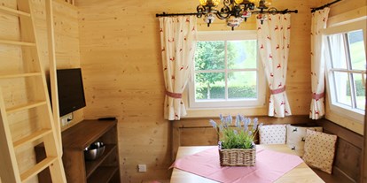 Luxuscamping - Umgebungsschwerpunkt: See - Ferienhütte "Drachenwand": gemütliche Sitzecke mit Fernseher (SAT-Anlage) und Aufgang zur Galerie mit Schlafmöglichkeit - CAMP MondSeeLand