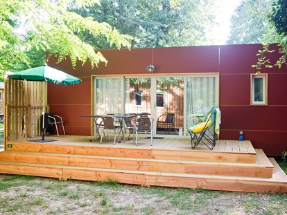 Luxuscamping - Art der Unterkunft: Mobilheim - Divonne-les-Bains - Mobilheim Indigo - Aussenansicht mit Terrasse   - Camping Huttopia Divonne Mobilheim Indigo auf Camping Huttopia Divonne