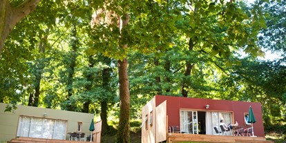 Luxuscamping - Gartenmöbel - Haut-Savoie - Mobilheim Indigo - Aussenansicht mit Terrasse - Camping Huttopia Divonne Mobilheim Indigo auf Camping Huttopia Divonne