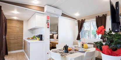 Luxuscamping - Cavallino-Treporti - Wohnzimmer mit Küche und im unteren Schlafzimmer der Kinder - Camping Vela Blu Mobilheim Top Residence Platinum auf Camping Vela Blu