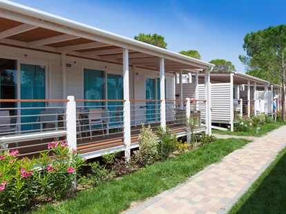 Luxuscamping - Dusche - Adria - Außenansicht des Mobilheims mit Terrasse - Camping Vela Blu Mobilheim Venezia Platinum auf Vela Blu Camping Village