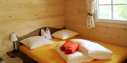 Luxuscamping - Gartenmöbel - Salzkammergut - Ferienhütte "Drachenwand": Schlafzimmer mit Doppelbett - CAMP MondSeeLand Ferienhütten am CAMP MondSeeLand