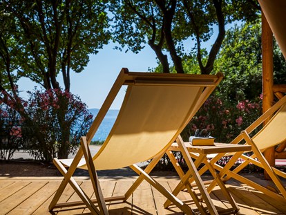 Luxuscamping - Art der Unterkunft: Safari-Zelt - Kroatien - Große überdachte Terrasse mit zwei Sonnenliegen und Lounge-Sesseln - Krk Premium Camping Resort - Valamar Krk Premium Camping Resort - Safari-Zelte