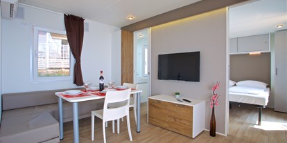 Luxuscamping - Kochmöglichkeit - Wohnzimmer mit Esstisch und Stühlen
 - Camping Cikat Mobilheime Typ C auf Camping Cikat
