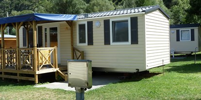 Luxuscamping - Parkplatz bei Unterkunft - PLZ 3942 (Schweiz) - Die Mietunterkünfte sind ausgestattet mit Schlafzimmer (1 Bett: 140 x 200cm), Kinderzimmer (2 Betten: 80 x 200cm), Dusche/WC, Wohnküche mit SAT-TV und gedeckter Veranda mit Tisch und Stühlen. Pfannen, Besteck, Geschirr und Gläser, Bettdecken und Kopfkissen sind ebenfalls vorhanden. - Camping Santa Monica Mobilheime am Camping Santa Monica