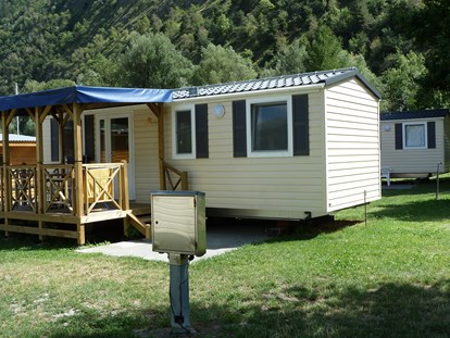 Luxuscamping - Kühlschrank - PLZ 3942 (Schweiz) - Die Mietunterkünfte sind ausgestattet mit Schlafzimmer (1 Bett: 140 x 200cm), Kinderzimmer (2 Betten: 80 x 200cm), Dusche/WC, Wohnküche mit SAT-TV und gedeckter Veranda mit Tisch und Stühlen. Pfannen, Besteck, Geschirr und Gläser, Bettdecken und Kopfkissen sind ebenfalls vorhanden. - Camping Santa Monica Mobilheime am Camping Santa Monica