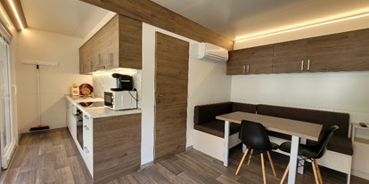 Luxuscamping - Parkplatz bei Unterkunft - PLZ 3942 (Schweiz) - Die Mietunterkünfte sind ausgestattet mit Schlafzimmer (1 Doppelbett: 160 x 200cm), 1 Schlafzimmer mit einem Doppelbett (160 cm x 200 cm und einem Kajütenbett (80 x 200cm, max. 60 Kg) Dusche/WC, Wohnküche mit SAT-TV und gedeckter Veranda mit Tisch und Stühlen. Pfannen, Besteck, Microwelle, Kapselmaschine (Tassimo) Geschirr und Gläser, Bettdecken und Kopfkissen sind ebenfalls vorhanden. - Camping Santa Monica Bungalows Typ Marisol am Camping Santa Monica