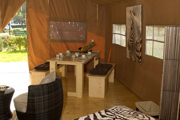 Glampingunterkunft: Blick vom Safarizelt auf die Terrasse. Dort gibt es ebenfalls einen langen Tisch und Bänke - für ein Abendessen bei Sonnenuntergang. - Safarizelte Camping Park Gohren