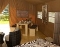 Glampingunterkunft: Blick vom Safarizelt auf die Terrasse. Dort gibt es ebenfalls einen langen Tisch und Bänke - für ein Abendessen bei Sonnenuntergang. - Safarizelte Camping Park Gohren