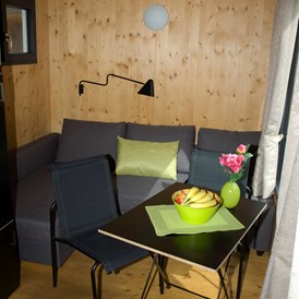 Glampingunterkunft: Innenansicht der Minilodges. Die Sitzgruppe kann in ein bequemes Doppelbett umfunktioniert werden. - Minilodges Camping Park Gohren