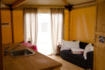 Glampingunterkunft: Glamping-Zelte: Wohnzimmer mit Tisch, Stühlen, Spülbecken, Kühlschrank (ohne Küche) und Schlafsofa - Glampingzelte auf Camping Rialto