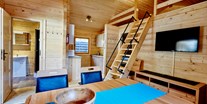Luxuscamping - Wohnbereich mit Aufgang zum Schlafboden bzw. Relaxlounge, gemütliche Sitzecke mit Blick zum Flat-TV, Pelletsofen - Camping Dreiländereck in Tirol Blockhütte Bergzauber Camping Dreiländereck Tirol