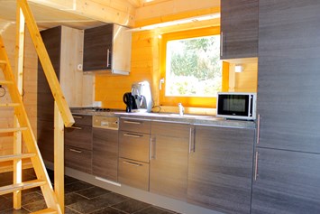 Glampingunterkunft: Küchenzeile mit Kochgelegenheit, Spülmaschine, Mikrowelle und Kaffeemaschine - Blockhäuser auf Camping Langenwald