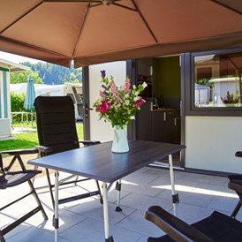 Glampingunterkunft: geräumige, sonnige Terrasse mit Gartenmöbeln und Sonnenschirm - Luxuswohnwagen Premium in Kirchzarten / Schwarzwald