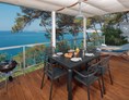 Glampingunterkunft: große und überdachte Terrasse mit einem Außensofa, Liegestühlen und einem wunderschönen Meerblick - Mobilheim Premium Vista Mare auf Lanterna Premium Camping Resort