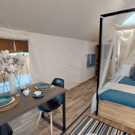 Glamping: Lakeside romantic Tent Schlafzimmer mit Doppelbett und der Sitz- bzw. Essbereich - Lakeside Petzen Glamping Resort