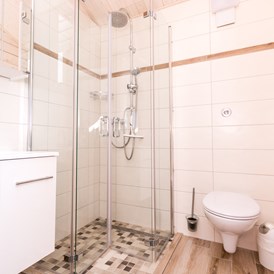 Glamping: Badezimmer im Ferienhäuschen mit bodentiefer Regendusche, WC und Spiegelschrank.  - Ostseecamping Ferienpark Zierow