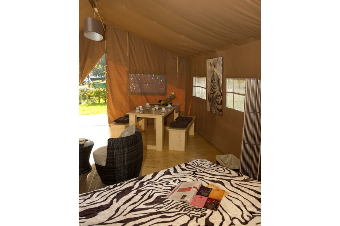 Glamping: Blick vom Safarizelt auf die Terrasse. Dort gibt es ebenfalls einen langen Tisch und Bänke - für ein Abendessen bei Sonnenuntergang. - Camping Park Gohren