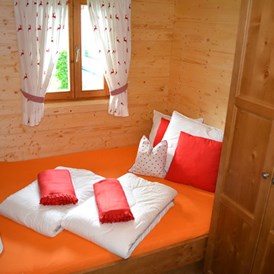 Glamping: Ferienhütte "Schober": Schlafzimmer mit Doppelbett und einem Stockbett - CAMP MondSeeLand