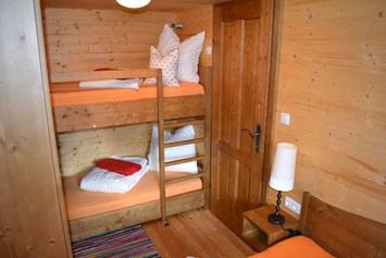Glamping: Ferienhütte "Schober": Schlafzimmer mit Doppelbett und einem Stockbett - CAMP MondSeeLand