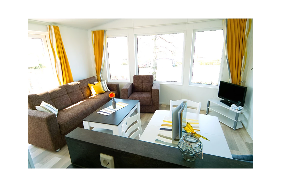 Glampingunterkunft: Wohnzimmer mit Sat-TV und gemütlicher Couch - Bungalow Möwe am Ostseecamp Seeblick