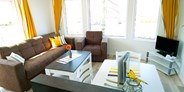 Luxuscamping - Umgebungsschwerpunkt: Meer - Wohnzimmer mit Sat-TV und gemütlicher Couch - Bungalow Möwe am Ostseecamp Seeblick