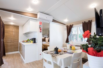 Glampingunterkunft: Wohnzimmer mit Küche und im unteren Schlafzimmer der Kinder - Mobilheim Top Residence Platinum auf Camping Vela Blu